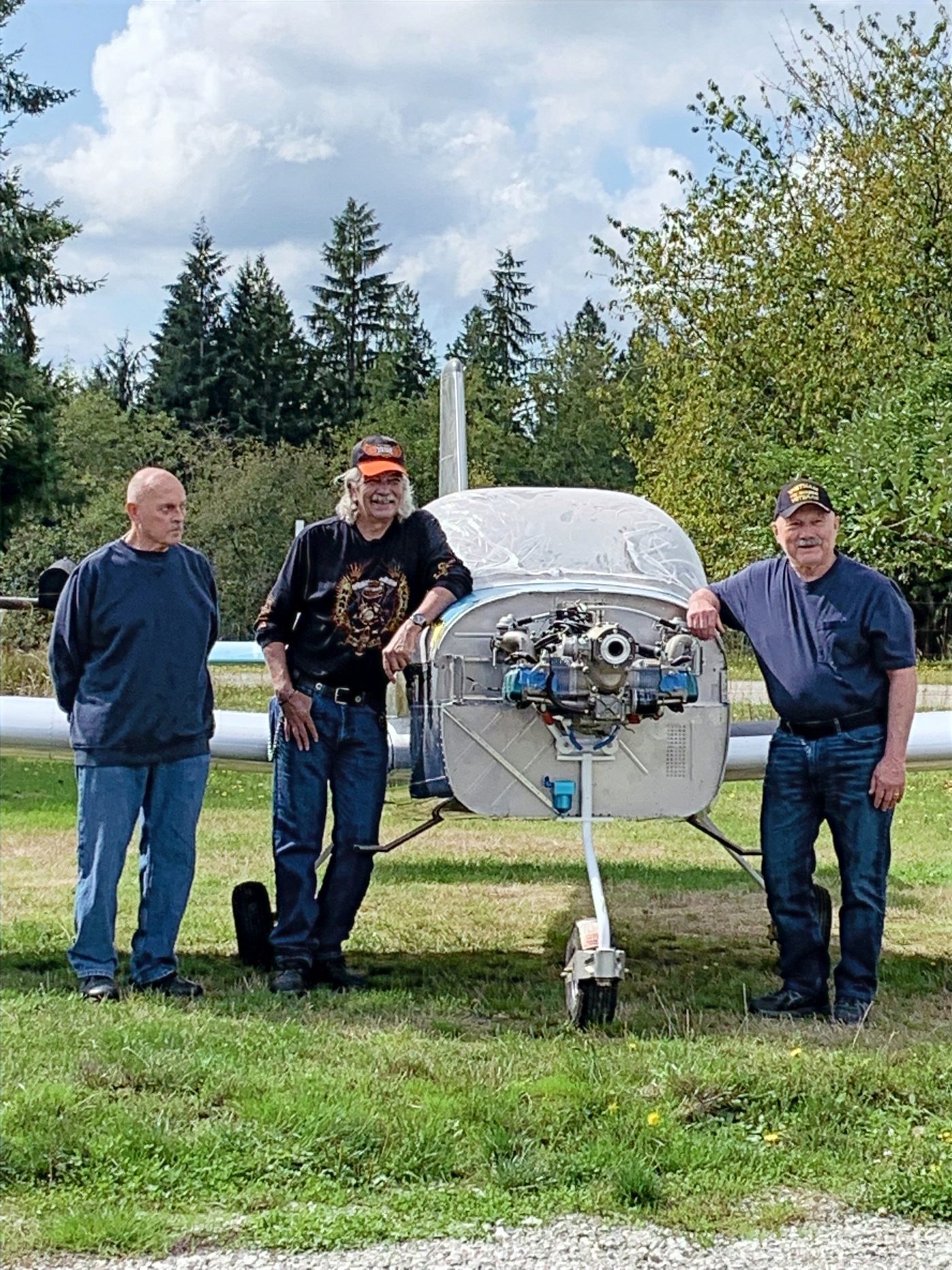 Three members with the aircraft outside on the lawn
